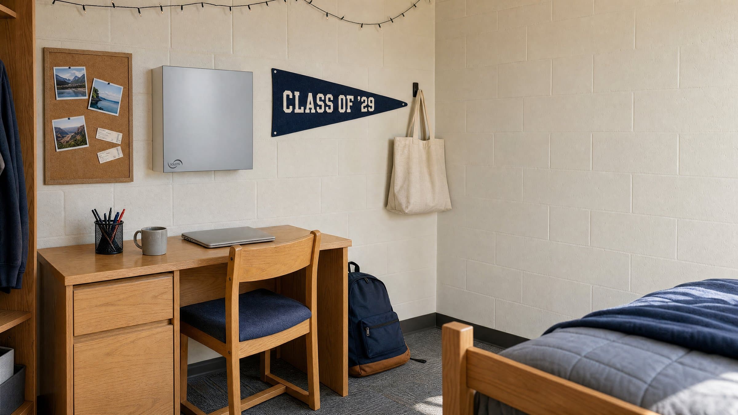 A dorm room in daylight: the Solstis cabinet, closed, hangs on the wall beside a desk and a bed